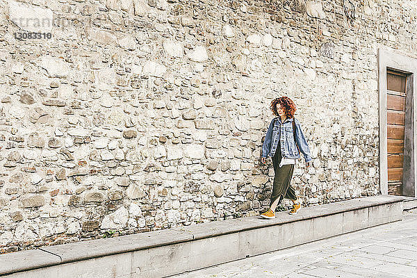 Frau geht auf einem Fußweg durch ein altes Gebäude in der Stadt