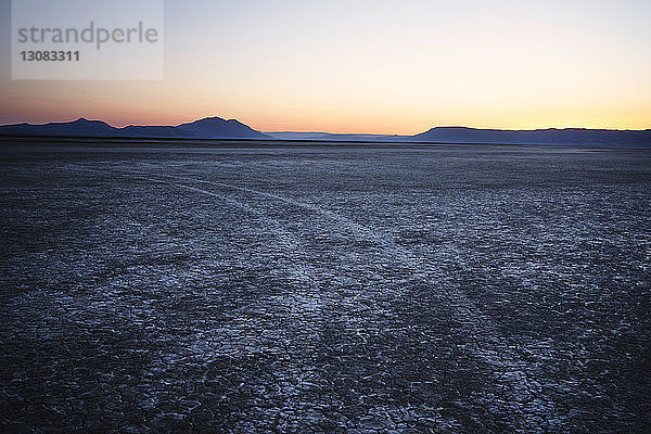 Szenische Ansicht des Feldes und der Berge gegen den Himmel bei Sonnenuntergang in der Alvord-Wüste