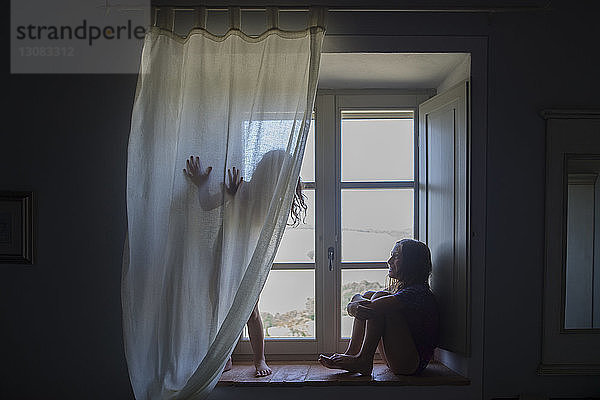 Schwestern auf der Fensterbank zu Hause