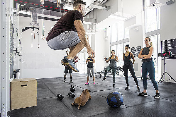 Ausbilder unterrichtet Athleten  während der Hund in der Crossfit-Turnhalle liegt