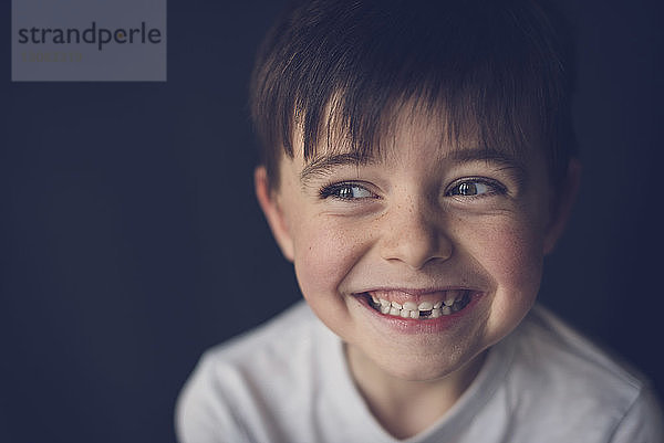 Nahaufnahme eines fröhlichen Jungen  der die Zähne zusammenbeißt  während er durch den Seitenblick blickt