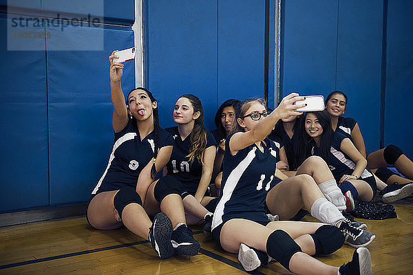 Spielerinnen  die auf dem Boden sitzen und sich auf dem Volleyballfeld klicken