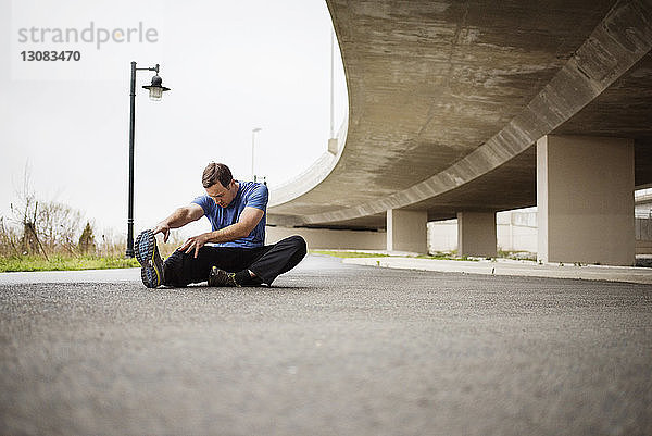 Entschlossener Mann trainiert  während er auf der Straße sitzt