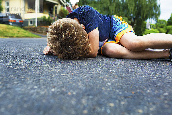 Trauriger Junge liegt auf der Straße