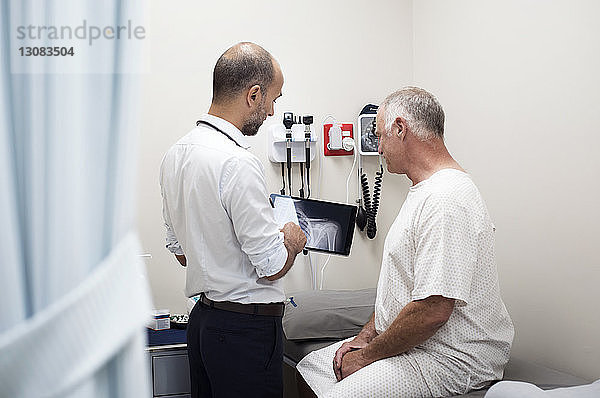 Arzt zeigt dem Patienten im Krankenhaus Röntgenberichte im Tablet-Computer