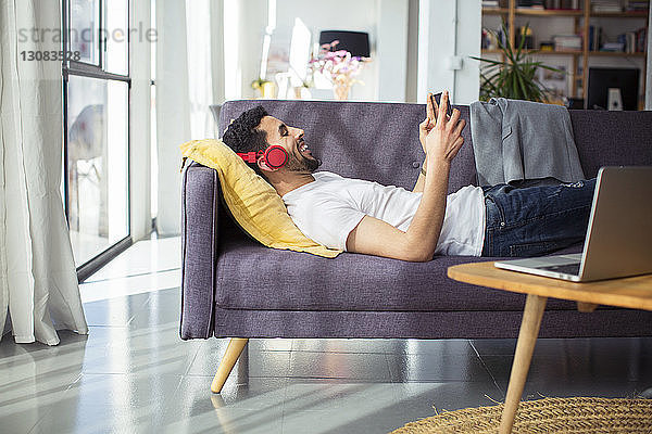 Glücklicher Geschäftsmann mit Tablet-Computer im Büro auf dem Sofa liegend