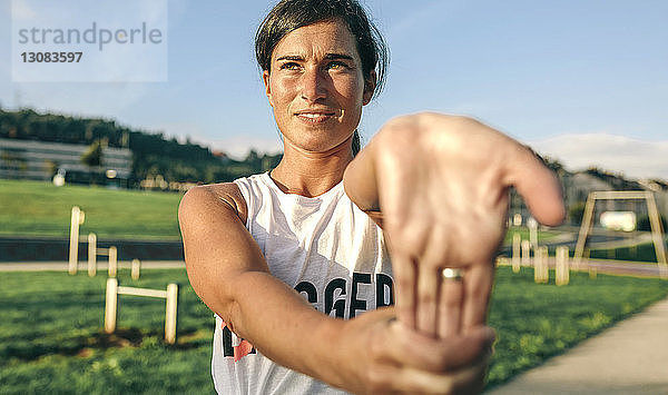 Frau dehnt Handgelenk beim Sport im Park