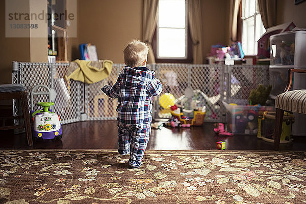 Rückansicht eines kleinen Jungen  der zu Hause auf dem Boden läuft