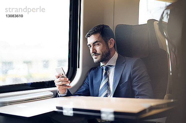 Geschäftsmann benutzt Smartphone während der Zugfahrt