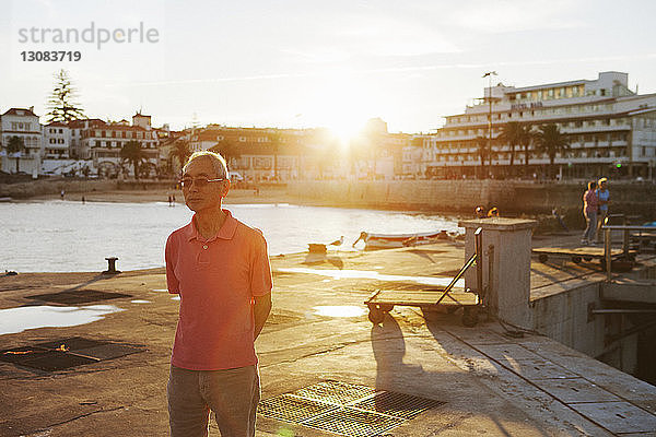 Mann steht am Hafen bei Sonnenuntergang gegen die Stadt