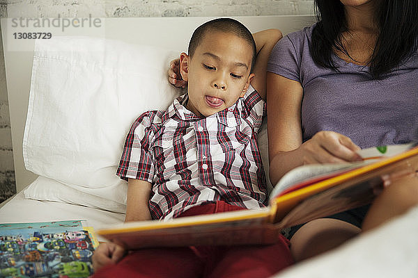 Junge hört Mutter zu Hause im Bett beim Buchlesen zu