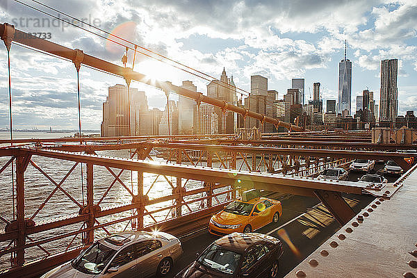 Fahrzeuge auf der Brooklyn Bridge mit der Skyline der Stadt im Hintergrund