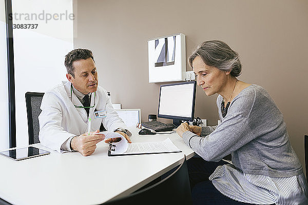 Arzt diskutiert mit Patient  während er im Krankenhaus an der Wand sitzt