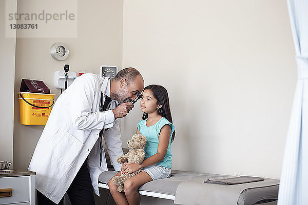 Arzt verwendet Otoskop zur Untersuchung des Ohrs eines Mädchens im medizinischen Untersuchungsraum