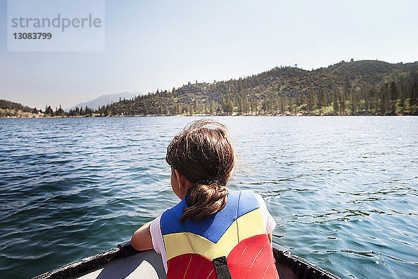 Rückansicht eines Mädchens mit Schwimmweste  das in einem Boot auf dem See sitzt