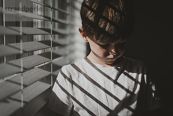 Junge steht zu Hause am Fenster