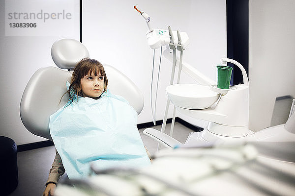 Lächelndes Mädchen sitzt in der Klinik auf dem Zahnarztstuhl