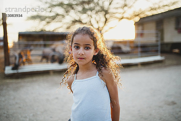 Porträt eines Mädchens  das bei Sonnenuntergang auf einem Bauernhof steht