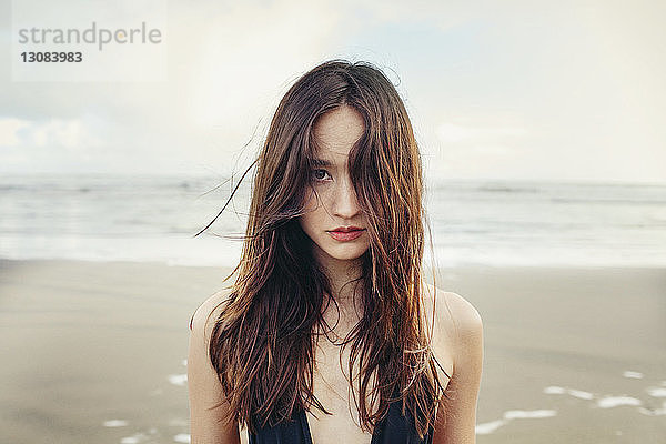 Porträt einer schönen Frau  die am Bethells-Strand gegen das Meer steht