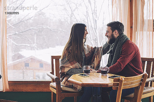 Glückliches Paar sieht sich an  während es im Café am Fenster sitzt