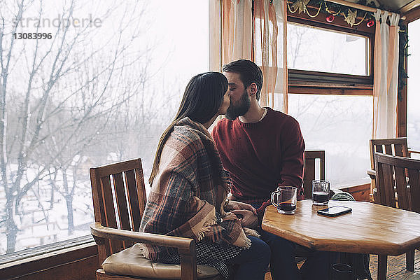 Junges Paar küsst sich im Winter im Cafe