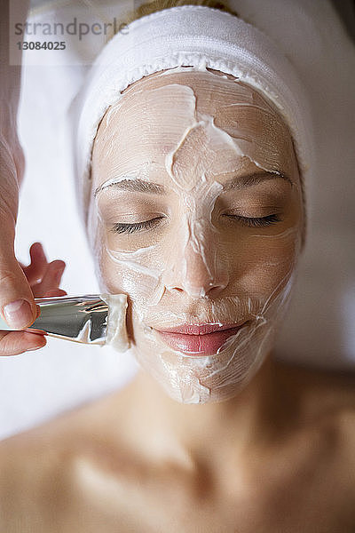 Draufsicht einer Gesichtsmaske  die im Spa auf das Gesicht einer Frau aufgetragen wird