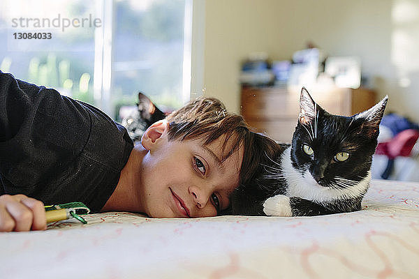 Porträt eines Jungen und einer Katze  die sich zu Hause auf dem Bett ausruhen