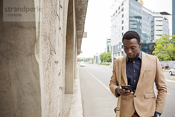 Geschäftsmann benutzt Smartphone auf der Straße in der Stadt