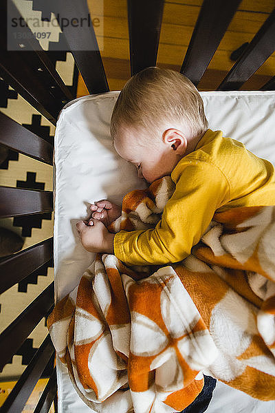 Draufsicht auf ein süßes Baby  das zu Hause im Gitterbett schläft