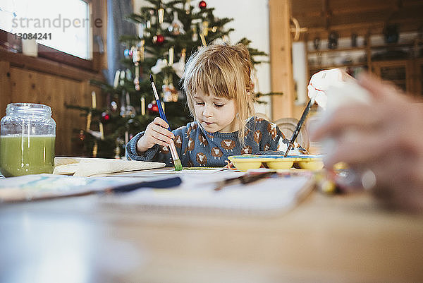 Mädchen malt zu Weihnachten zu Hause auf Papier