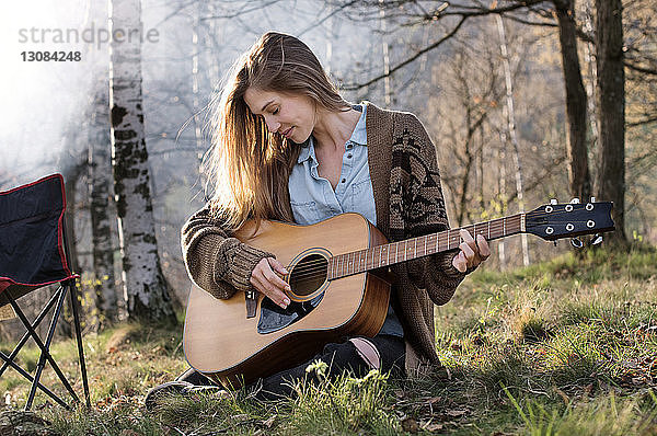 Schöne Frau spielt Gitarre im Wald