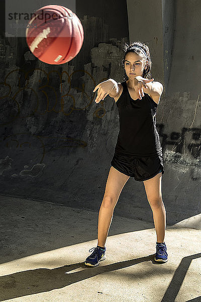 Selbstbewusster Sportler  der Basketball gegen die Wand spielt