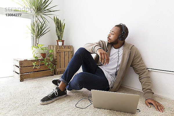 Geschäftsmann hört Musik  während er im Kreativbüro am Boden sitzt
