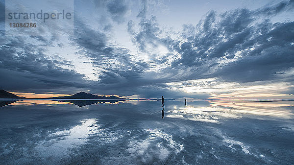 Silhouetten von Menschen  die auf den Bonneville Salt Flats vor bewölktem Himmel stehen