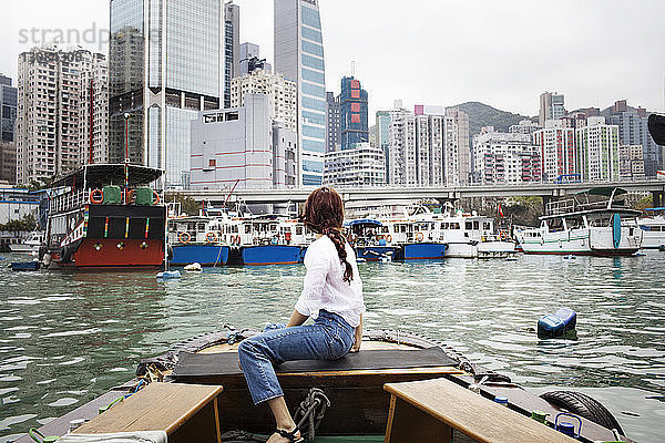 Seitenansicht einer Touristin  die im Boot sitzend auf Gebäude schaut