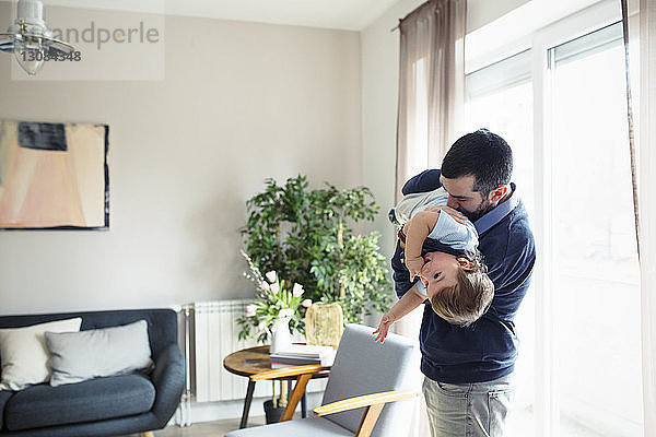 Verspielter Mann  der seinen Sohn zu Hause am Fenster trägt