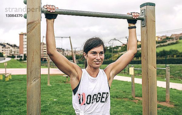 Selbstbewusste Frau hält Gymnastikbalken während des Trainings im Park