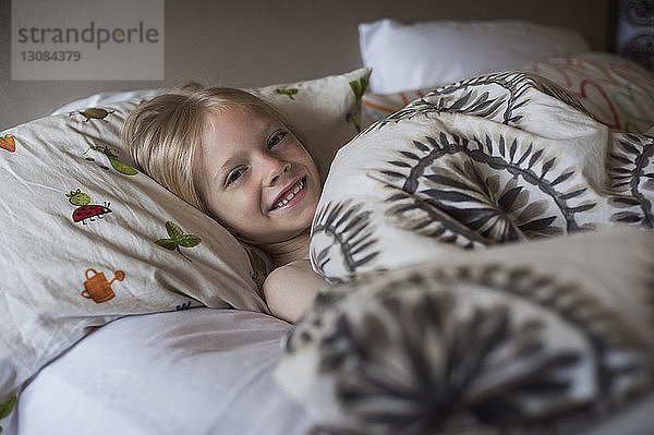 Porträt eines glücklichen Jungen im Bett liegend