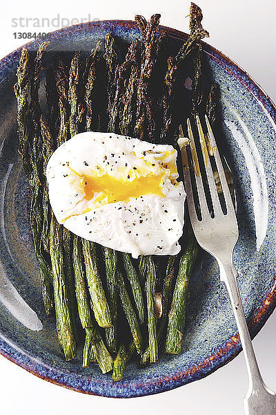 Draufsicht auf ein Ei mit Spargel  serviert in einem Teller auf weißem Hintergrund
