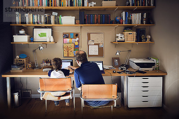 Vater hilft Sohn bei der Benutzung eines Laptops zu Hause