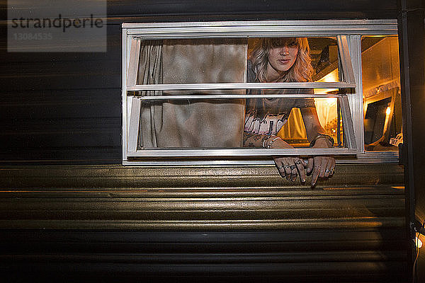 Porträt einer Frau  die durch ein Fenster aus einem Boutique-Trailer gesehen wurde