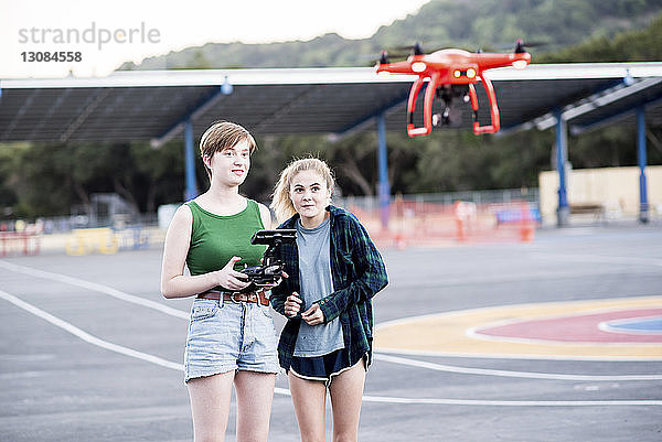 Freunde bedienen Quadcopter  während sie im Park stehen