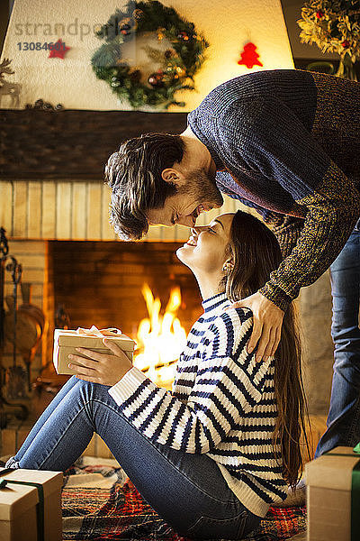 Romantisches Paar mit Weihnachtsgeschenk reibt sich zu Hause die Nasen