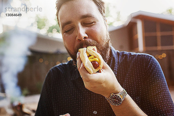 Mann isst Hot Dog im Hof