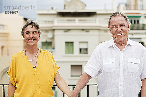 Porträt eines glücklichen älteren Paares auf der Terrasse stehend