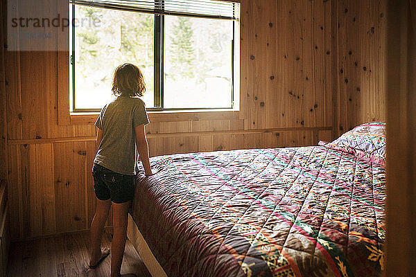 Rückansicht eines Mädchens  das neben dem Bett im Zimmer steht