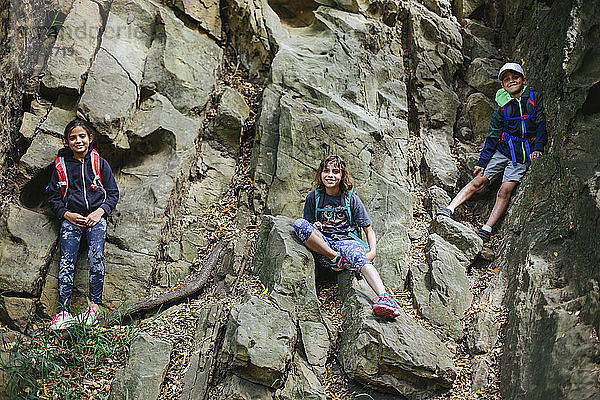 Niedrigwinkel-Porträt glücklicher Geschwister beim Klettern an Felsen