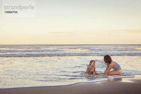 Schwester genießt am Strand am Strand während des Sonnenuntergangs