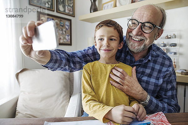Glücklicher älterer Mann  der mit seinem Enkel zu Hause Selfie nimmt