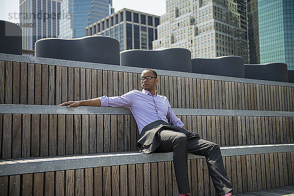 Niedrigwinkelansicht eines Geschäftsmannes  der auf Holzstufen gegen Gebäude sitzt